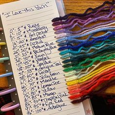 there are many different colored threads on the table next to an open notepad