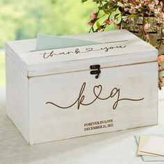 a white wooden box with writing on it and a flower pot behind it that says, thank you k e p