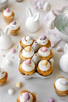 there are many cupcakes on the table with white frosting and candies