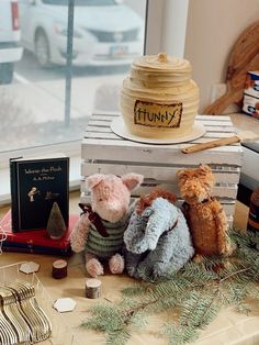 three stuffed animals sitting on top of a table next to a book and some other items