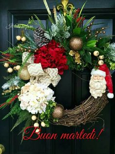 a christmas wreath with santa's hats and flowers hanging on a black front door