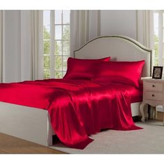 a bed with red sheets and pillows in a room