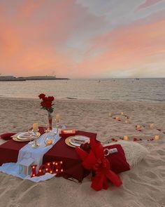 a table set up on the beach with candles and flowers