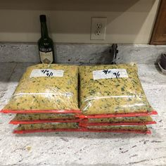 three bags of food sitting on top of a counter next to a bottle of wine