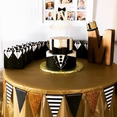 a black and white cake on top of a table with gold foiling around it