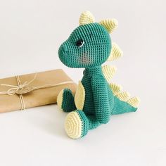 a crocheted toy sitting next to a present box and wrapped in brown paper