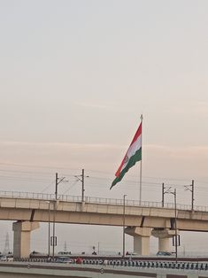 an italian flag is flying on the side of a bridge over water with cars driving under it