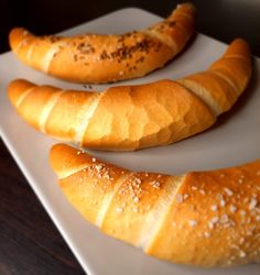 three loaves of bread sitting on top of a white plate next to each other