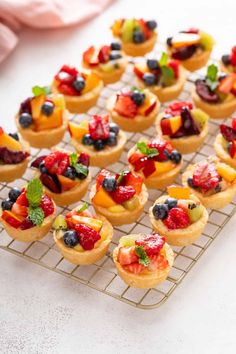 small fruit tarts are sitting on a cooling rack