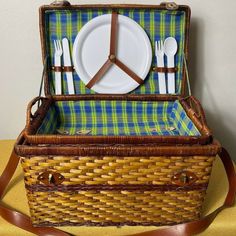 a wicker picnic basket with plates and utensils in it