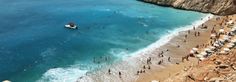 the beach is crowded with people and umbrellas as they swim in the ocean near cliffs