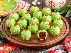 green and red desserts on a wooden platter with christmas decorations around the edges