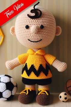 a crocheted doll sitting next to two soccer balls