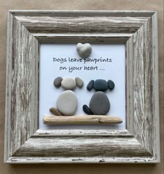 some rocks are sitting in a frame with the words dogs leave pawprints on your heart