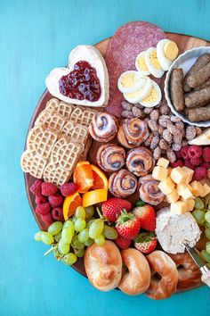 a platter filled with different types of food on a blue tablecloth, including fruit, sausages and waffles