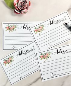 three place cards with flowers on them next to a pen and flower arrangement in the background