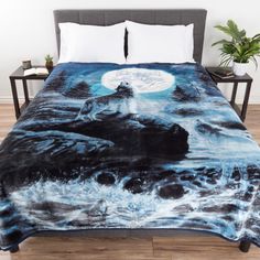 a bed covered in a black and white comforter with an ocean scene on it