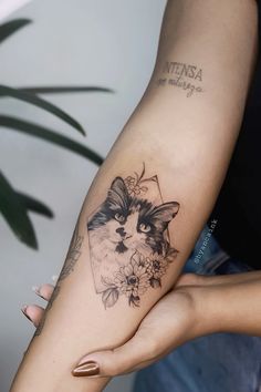 a woman with a cat tattoo on her arm holding onto another person's arm