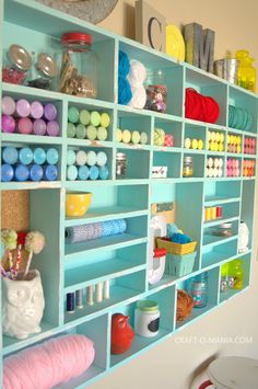 a blue shelf filled with lots of crafting supplies and yarn on top of it