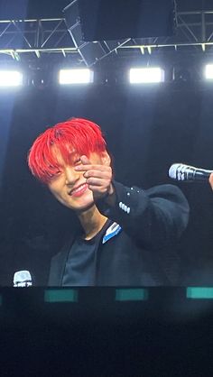 a man with red hair holding a microphone up to his face while standing on stage