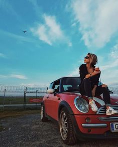 a woman sitting on top of a red car