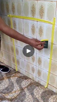 a person using a sponge to clean a tiled wall