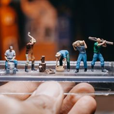 miniature figurines are sitting on top of a glass shelf in front of a person's hand