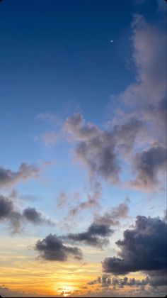 the sun is setting over the ocean with clouds in the sky and an airplane flying overhead