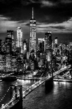 a black and white photo of the city skyline at night with lights from skyscrapers