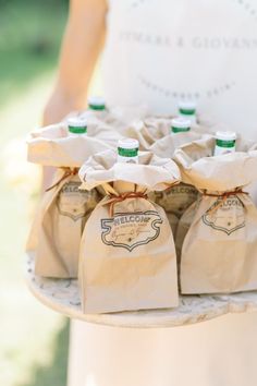 a person holding a tray with six bags on it and two green cups in the middle