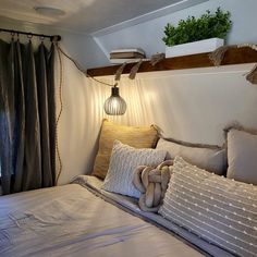 a bed with pillows and lights on the headboard in a room that looks like an rv