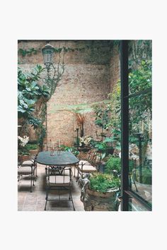 an outdoor dining area with potted plants on the wall and table in the middle