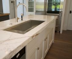 a kitchen with marble counter tops and stainless steel appliances in the center island, along with white cabinets