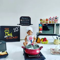 a baby sitting on top of a stove in front of a pot filled with food