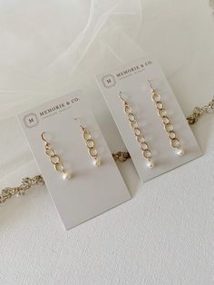 three pairs of earrings are on display in front of a white cloth covered tablecloth