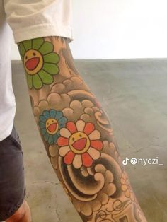 a person with a flower tattoo on their arm and leg is standing next to a skateboard