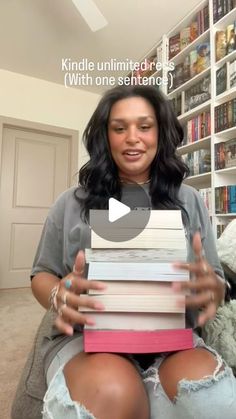 a woman sitting on top of a couch holding a stack of books