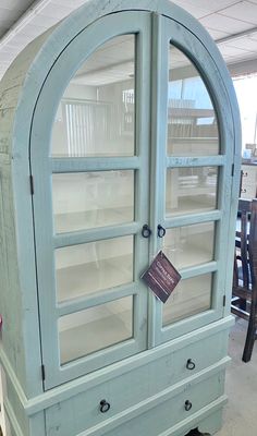 an old blue cabinet with glass doors in a store