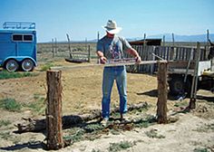 a man standing next to a blue truck on top of a dry grass covered field