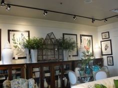 a living room filled with furniture and lots of plants on top of it's shelves