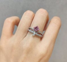 a woman's hand holding a pink and white diamond ring