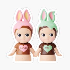 two small figurines with bunny ears on their heads, one holding the other's hand