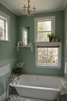 a bath tub sitting under two windows in a bathroom