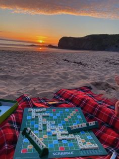 a person sitting on the beach with a board game in front of them and a book