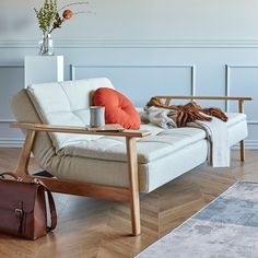 a white couch sitting on top of a hard wood floor next to a brown bag