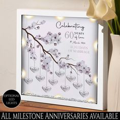 an anniversary card with flowers and hearts hanging from the strings in front of a vase