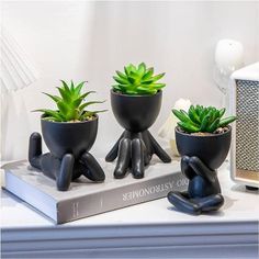 three black planters sitting on top of a book