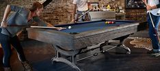 two people are playing pool in a bar