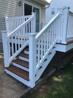 a set of stairs leading up to a house with white railings and wood steps