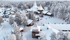 an aerial view of a village in the woods covered in snow and surrounded by trees